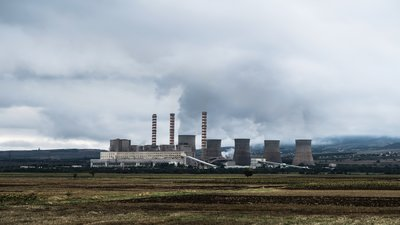 photo of power plant with smokestacks and cooling towers