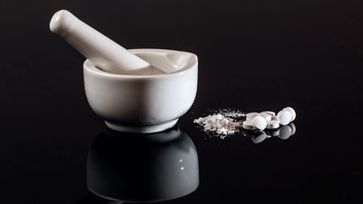 white pills next to mortar and pestle