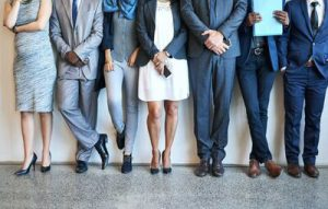 people dressed in business attire standing against a wall