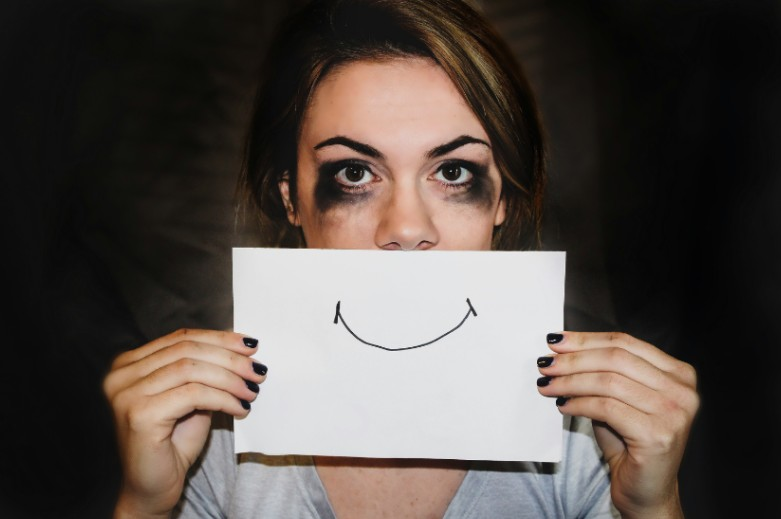 person holding piece of paper with smiley face drawing