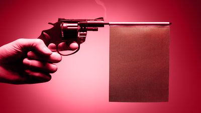 hand holding a gun with a red flag protruding from the barrel